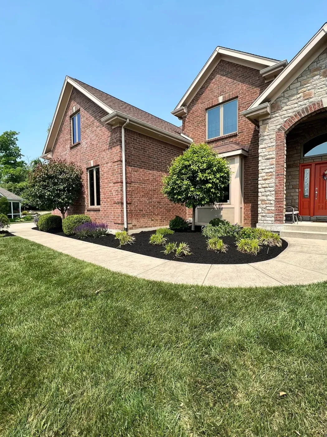 A mulched and planted bed curving around a brick home