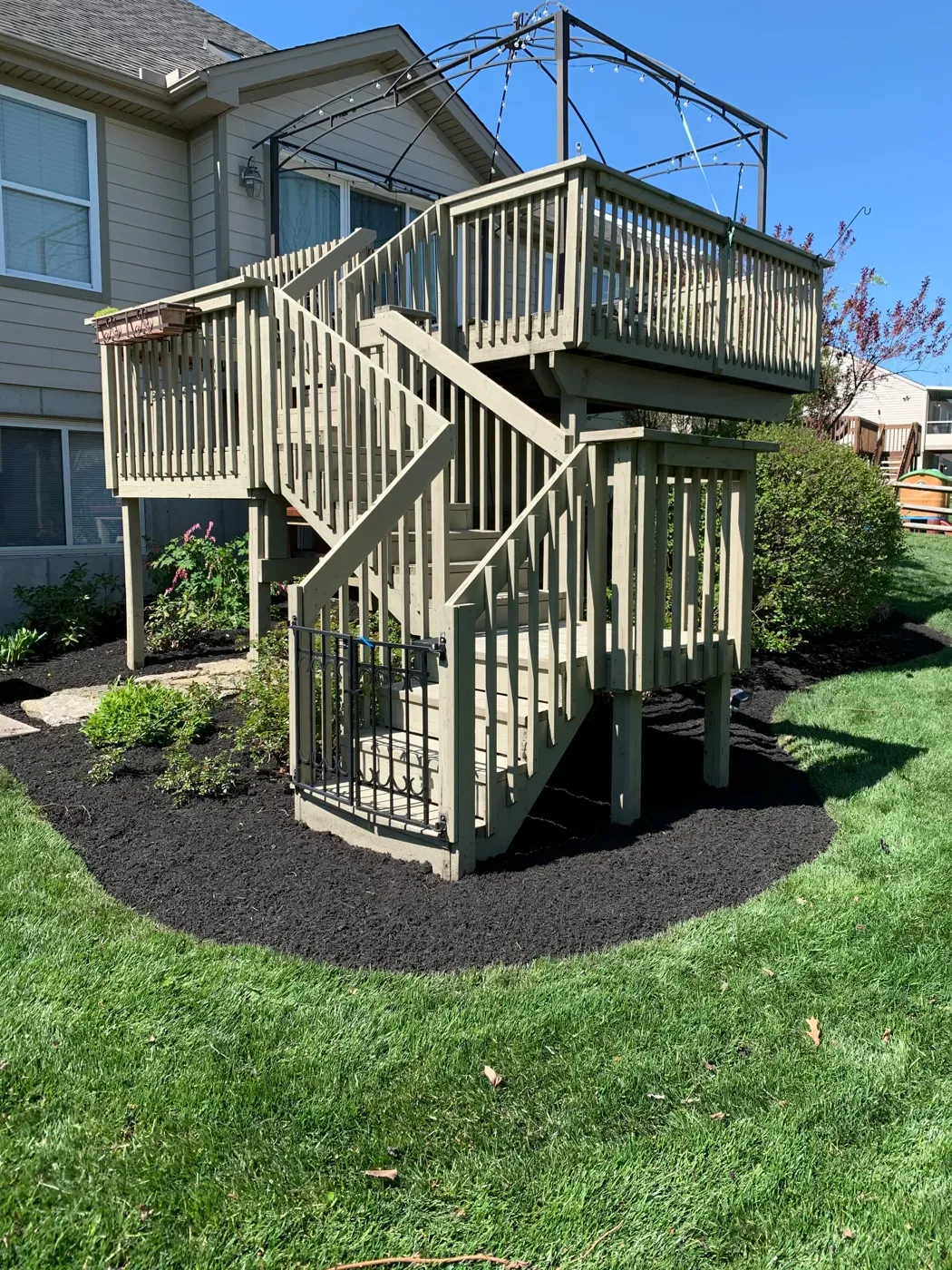New mulch beds wrapped around a backyard deck