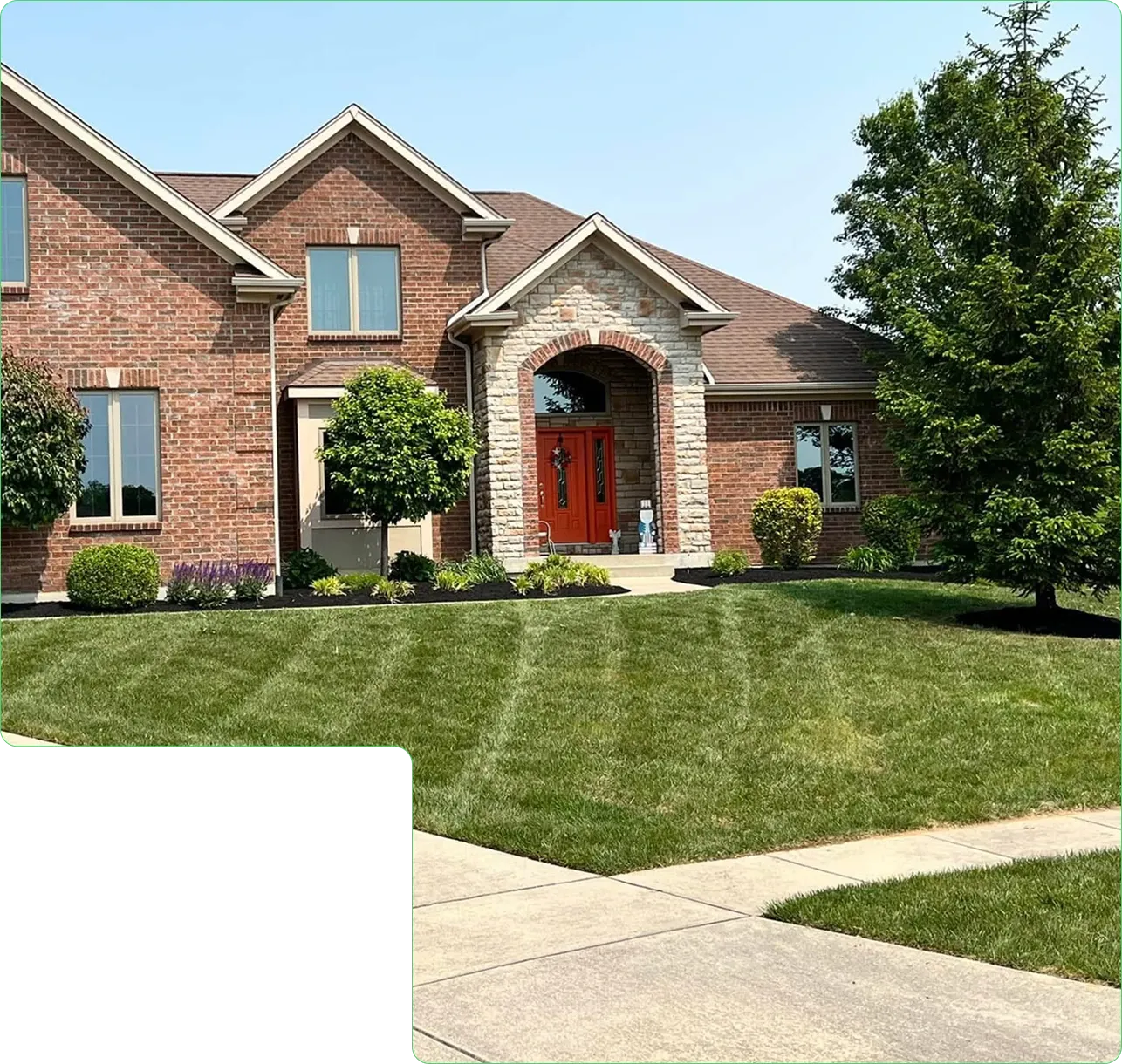 A freshly mowed and edged front lawn at a brick home in Dayton, Ohio by JBH Landscaping