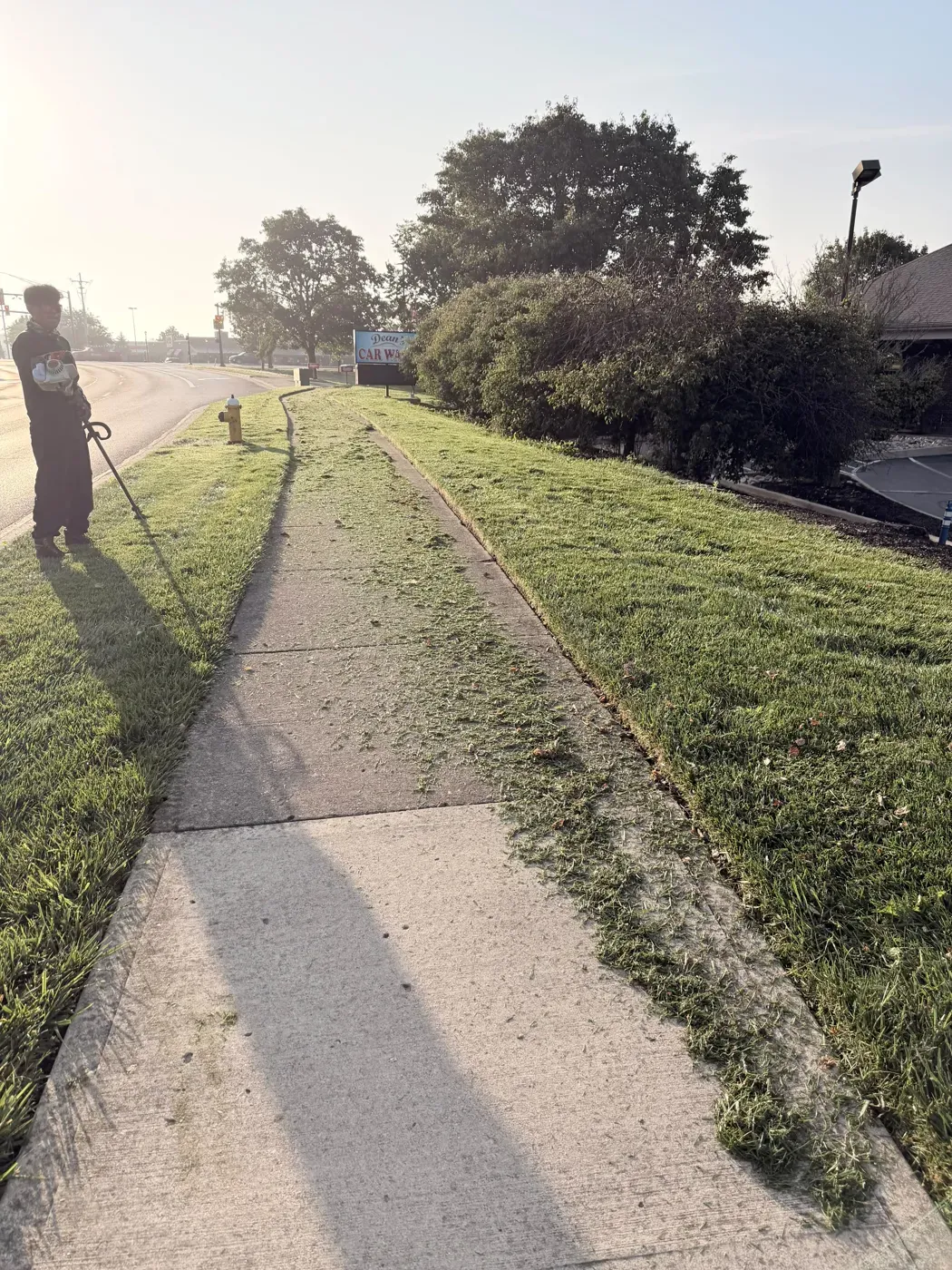 A JBH Landscaping crew member edging a sidewalk along a Dayton-area road