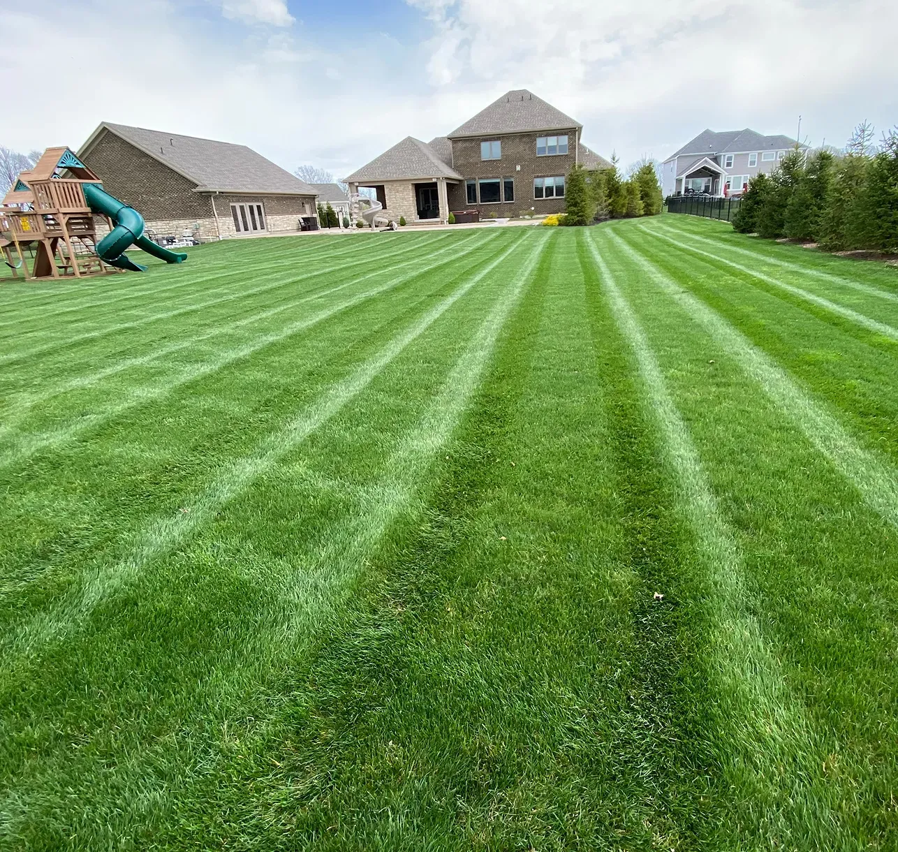 Mowing stripes across a large back yard with a playset in Dayton, Ohio