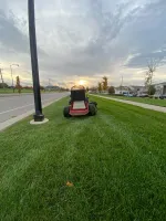 A mower parked on a freshly cut roadside lawn at sunset