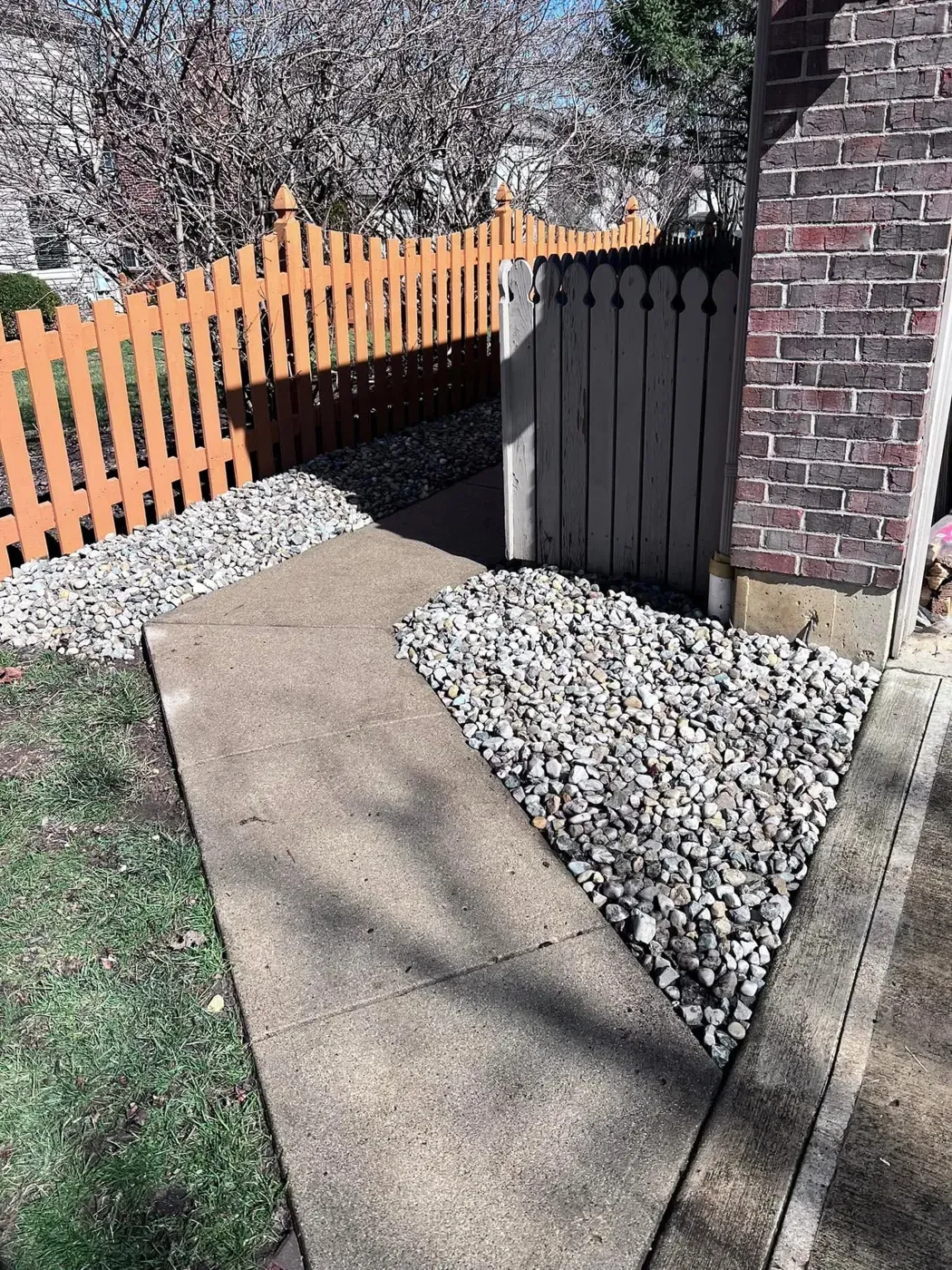 River rock laid along a side walkway beside a wooden fence