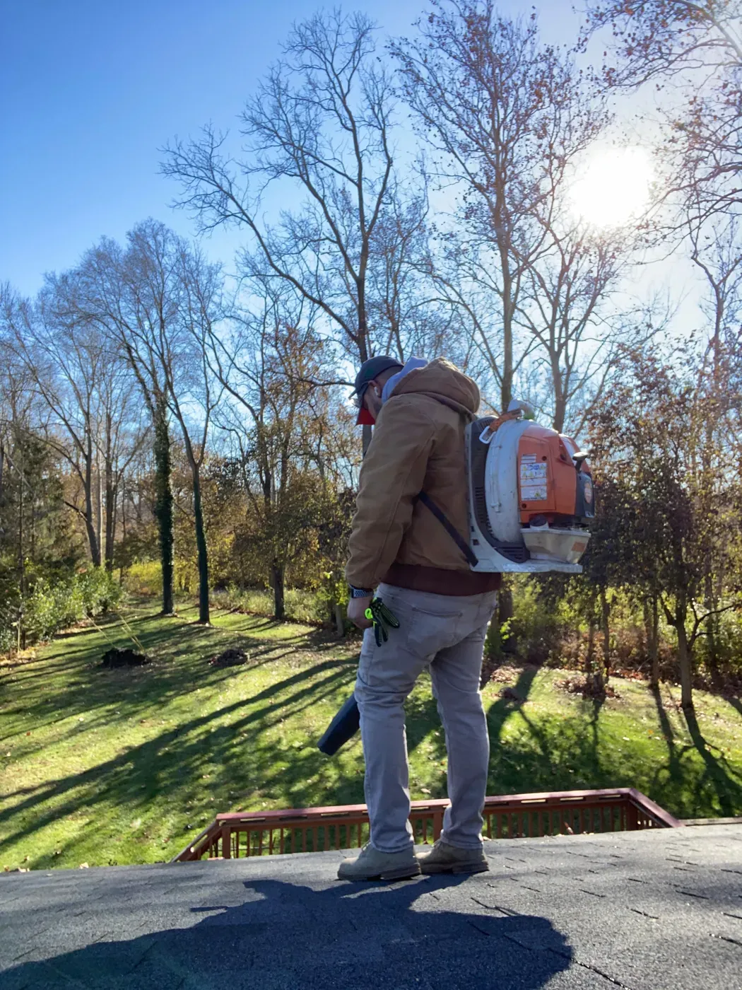 A JBH Landscaping crew member clearing fall leaves with a backpack blower