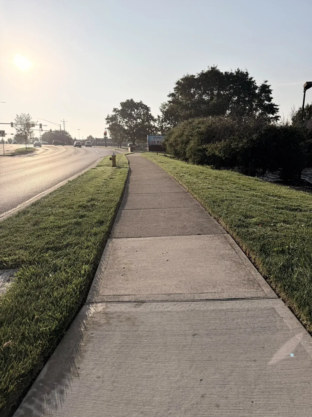 A sidewalk freshly edged on both sides along a busy road